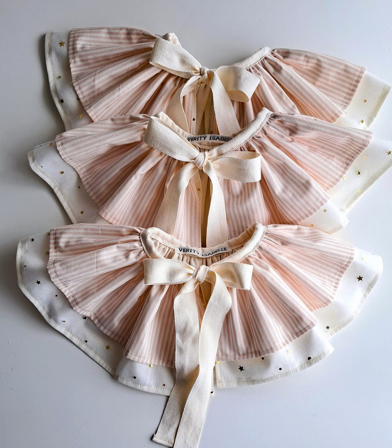 Handmade birthday pink striped capes laid flat on soft background