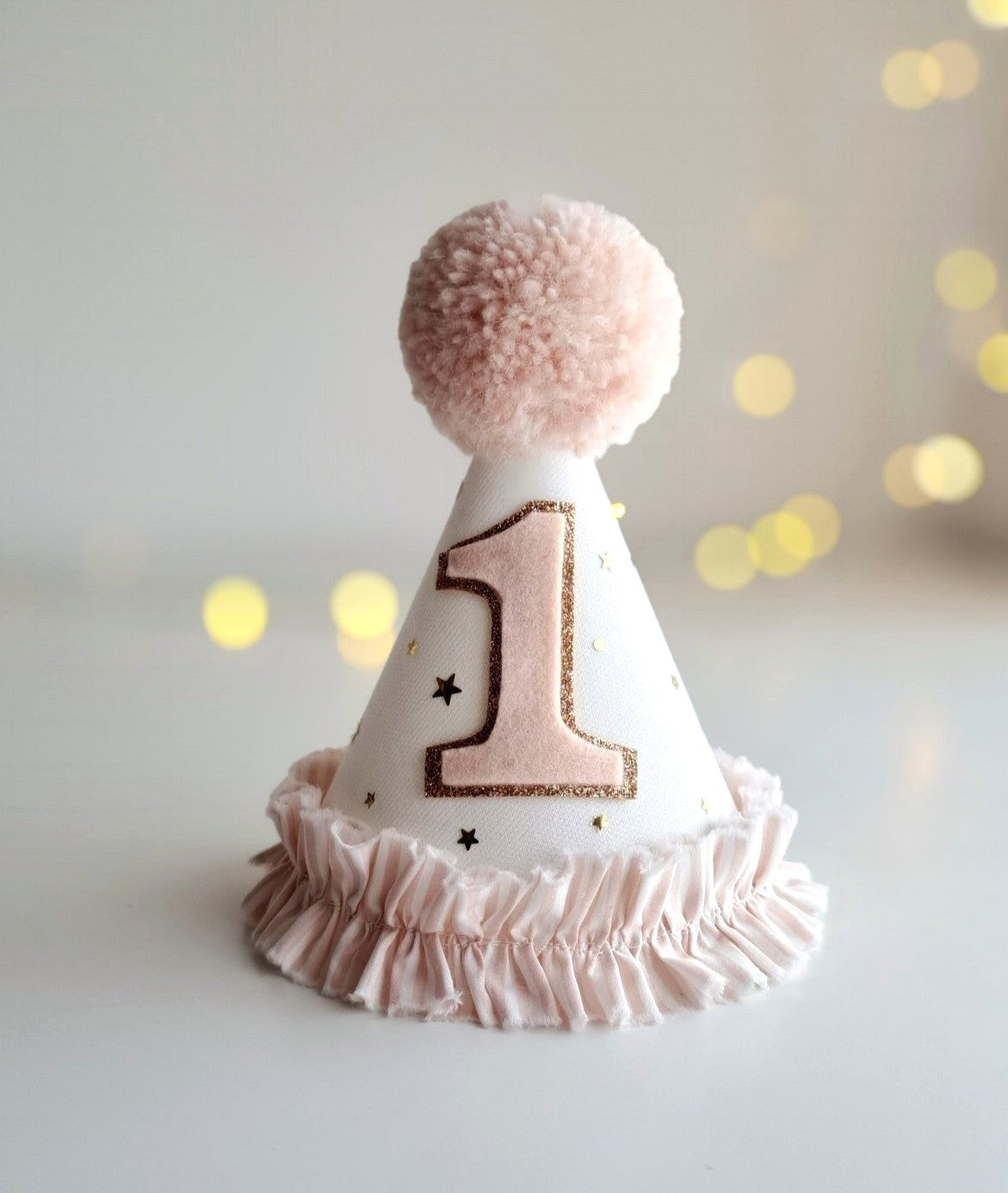 Close-up of pink linen party hat with felt birthday number and stripe ruffle