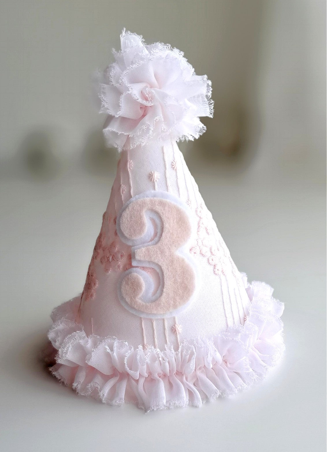 Soft pink princess birthday hat with felt number 3, embroidered lace fabric and white ruffle trim, handmade by Verity Isabelle.