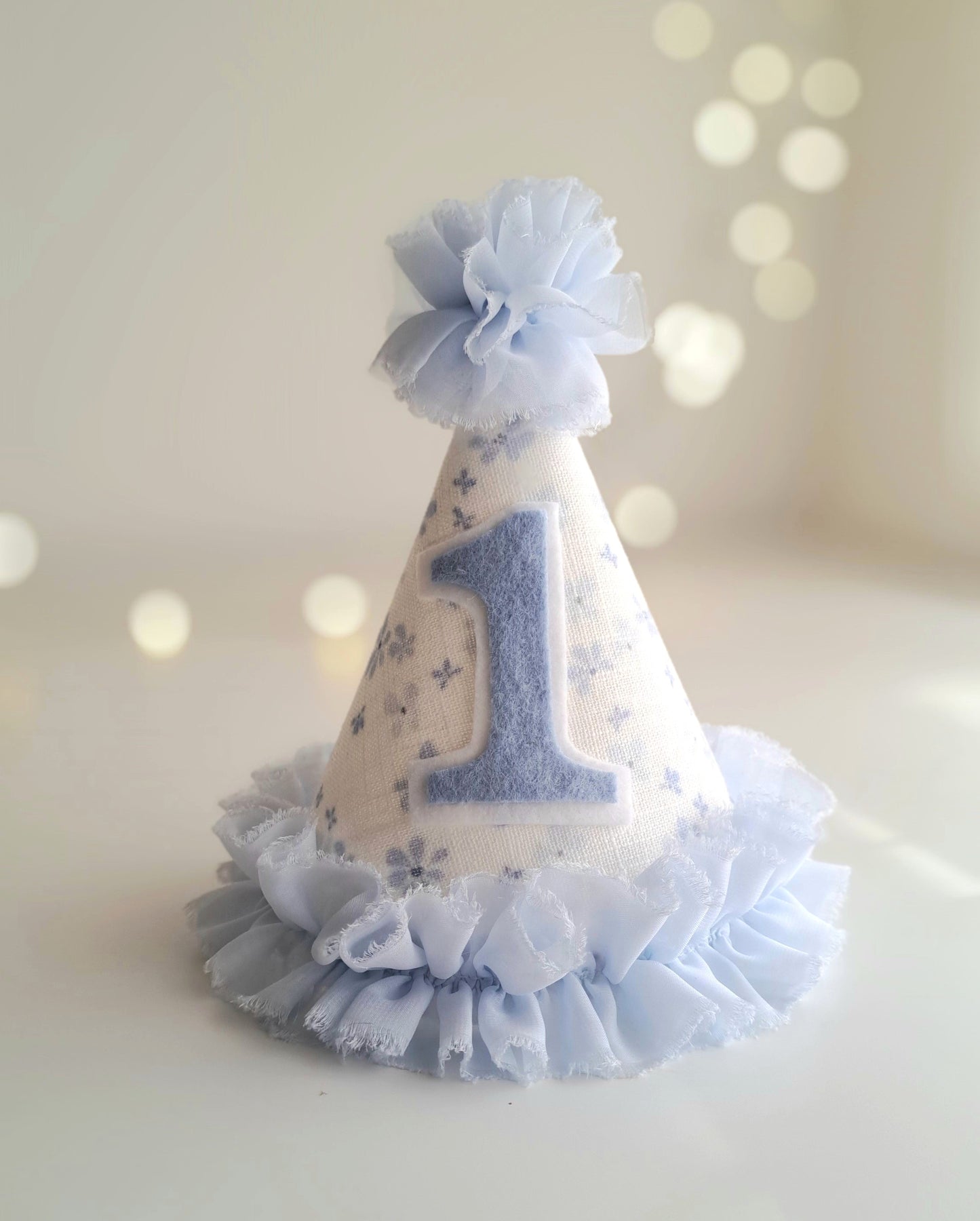 Blue number 1 birthday party hat with floral linen fabric, soft blue felt number and ruffle trim, handmade by Verity Isabelle.
