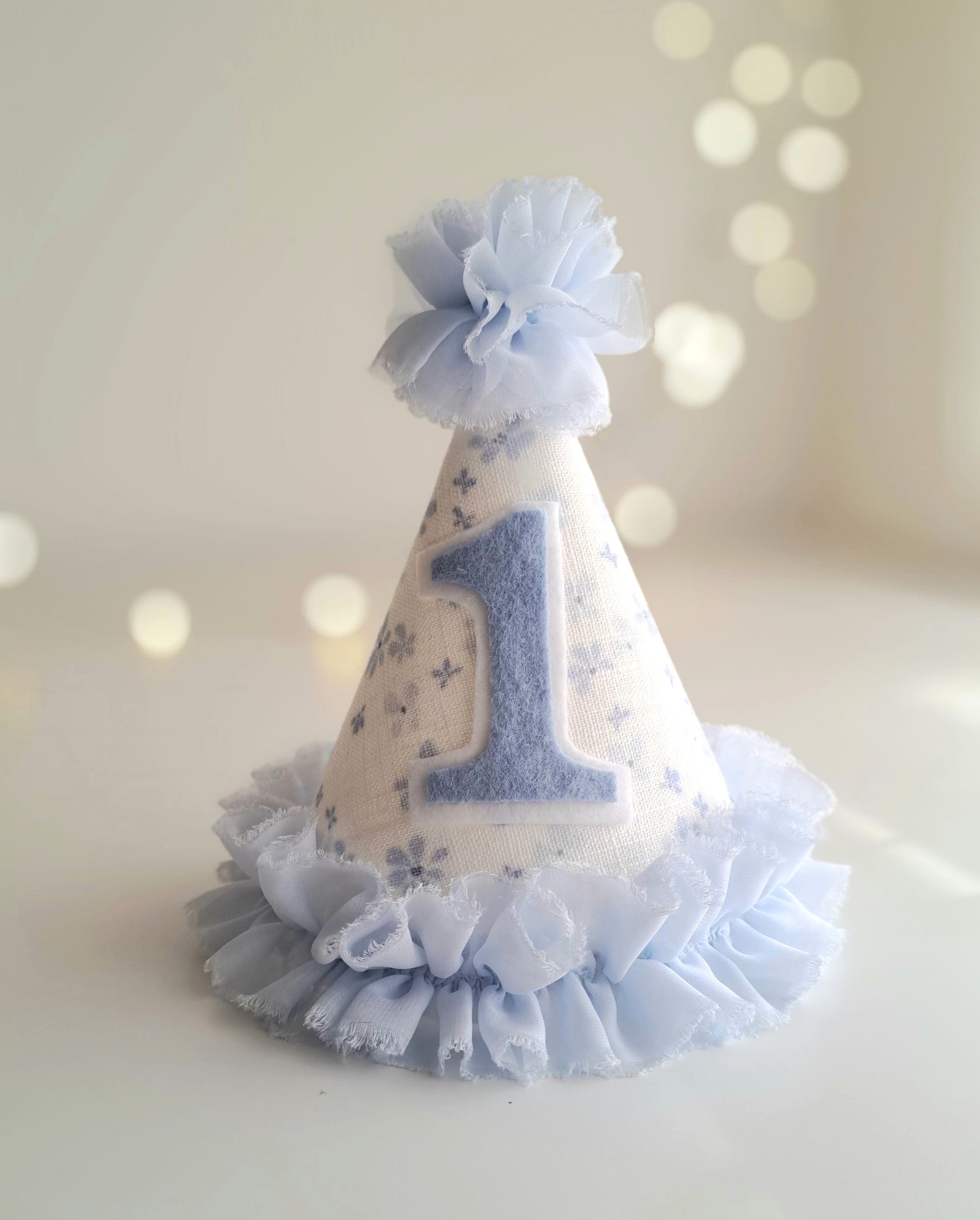 Blue number 1 birthday party hat with floral linen fabric, soft blue felt number and ruffle trim, handmade by Verity Isabelle.