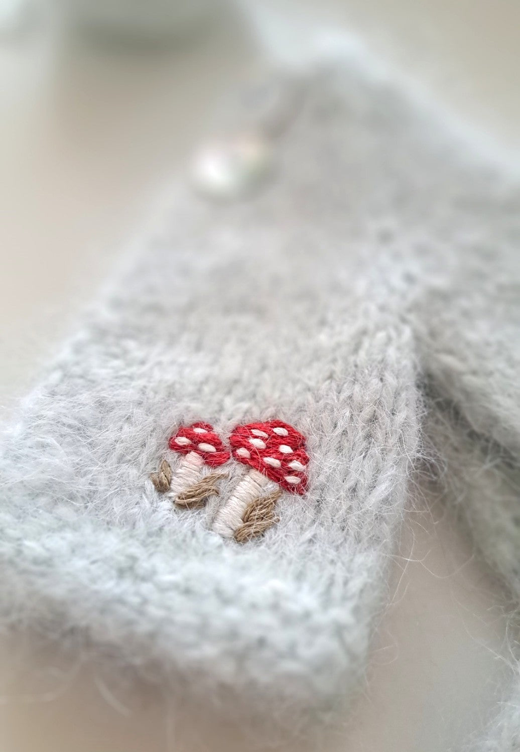 Detail of hand-embroidered forest mushrooms on Suri alpaca cardigan with mother-of-pearl buttons.