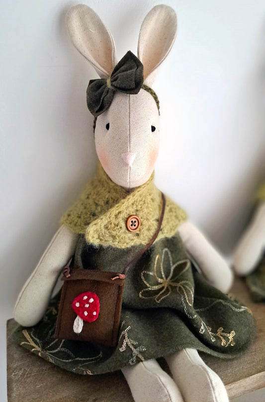 Handmade bunny toy carrying a brown felt bag with red mushroom applique