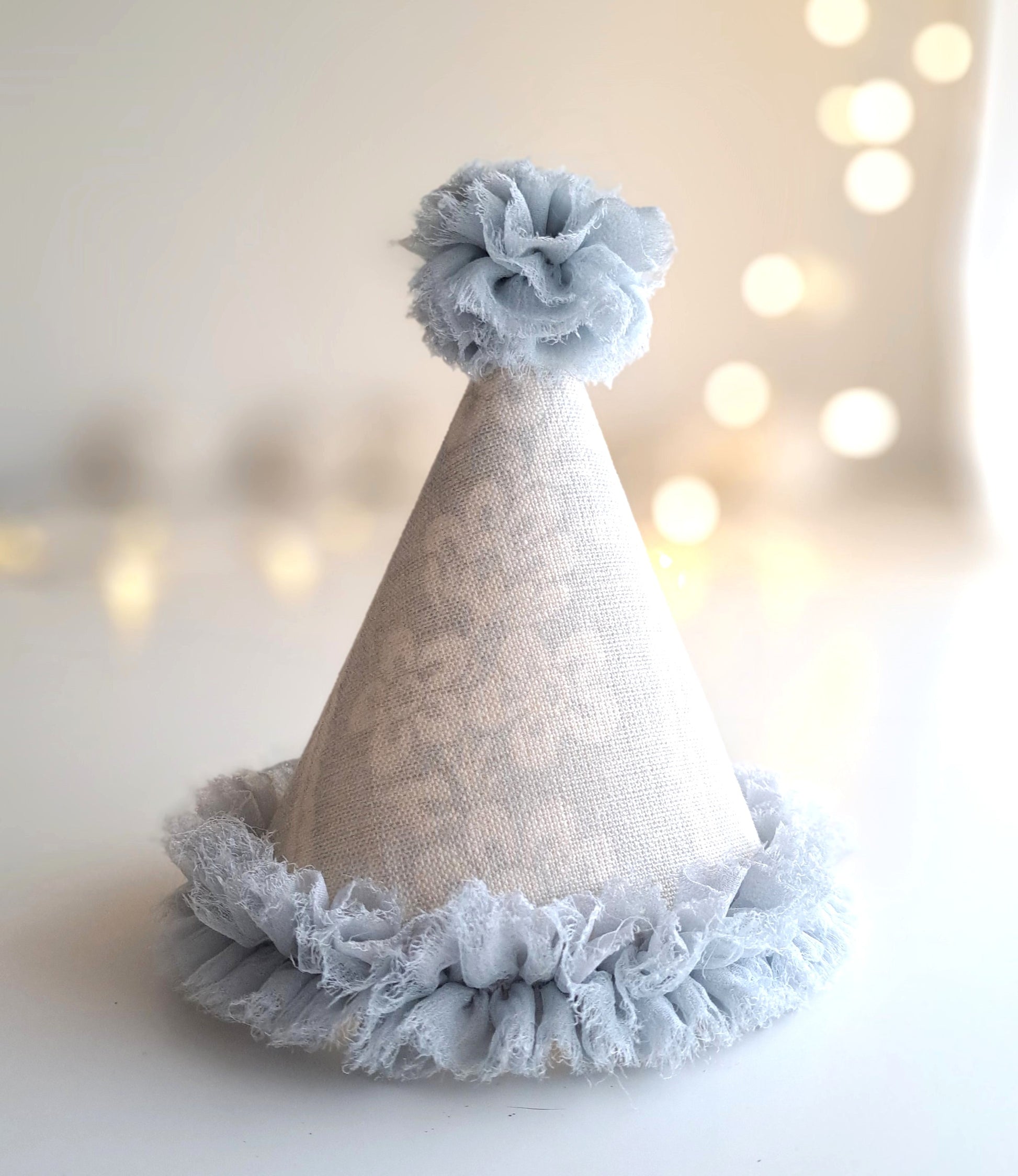 Pale blue ruffle linen party hat with soft blue fabric trim and pom pom, handmade by Verity Isabelle.