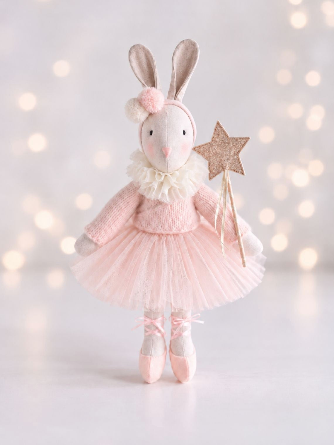 Handmade Verity Ballerina Bunny in a pink tutu and ballet shoes, holding a star wand against soft lights.