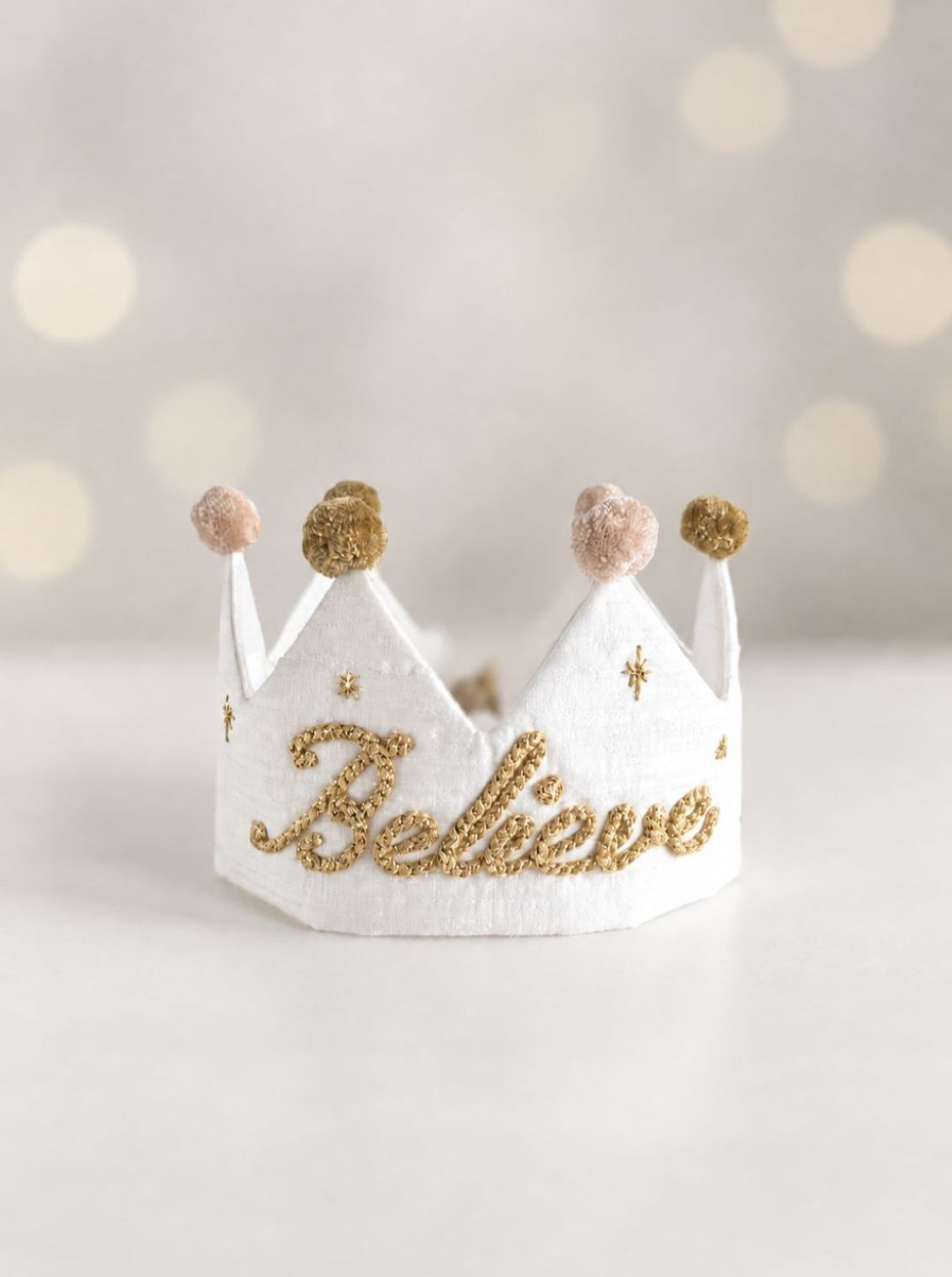 White Believe silk Christmas crown with gold embroidery and soft ivory and olive gold pom-poms.