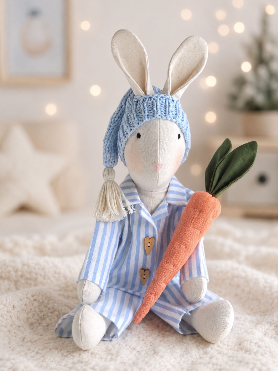 Handmade Gerald Bunny in blue striped Christmas pyjamas holding a linen carrot in a softly lit nursery.