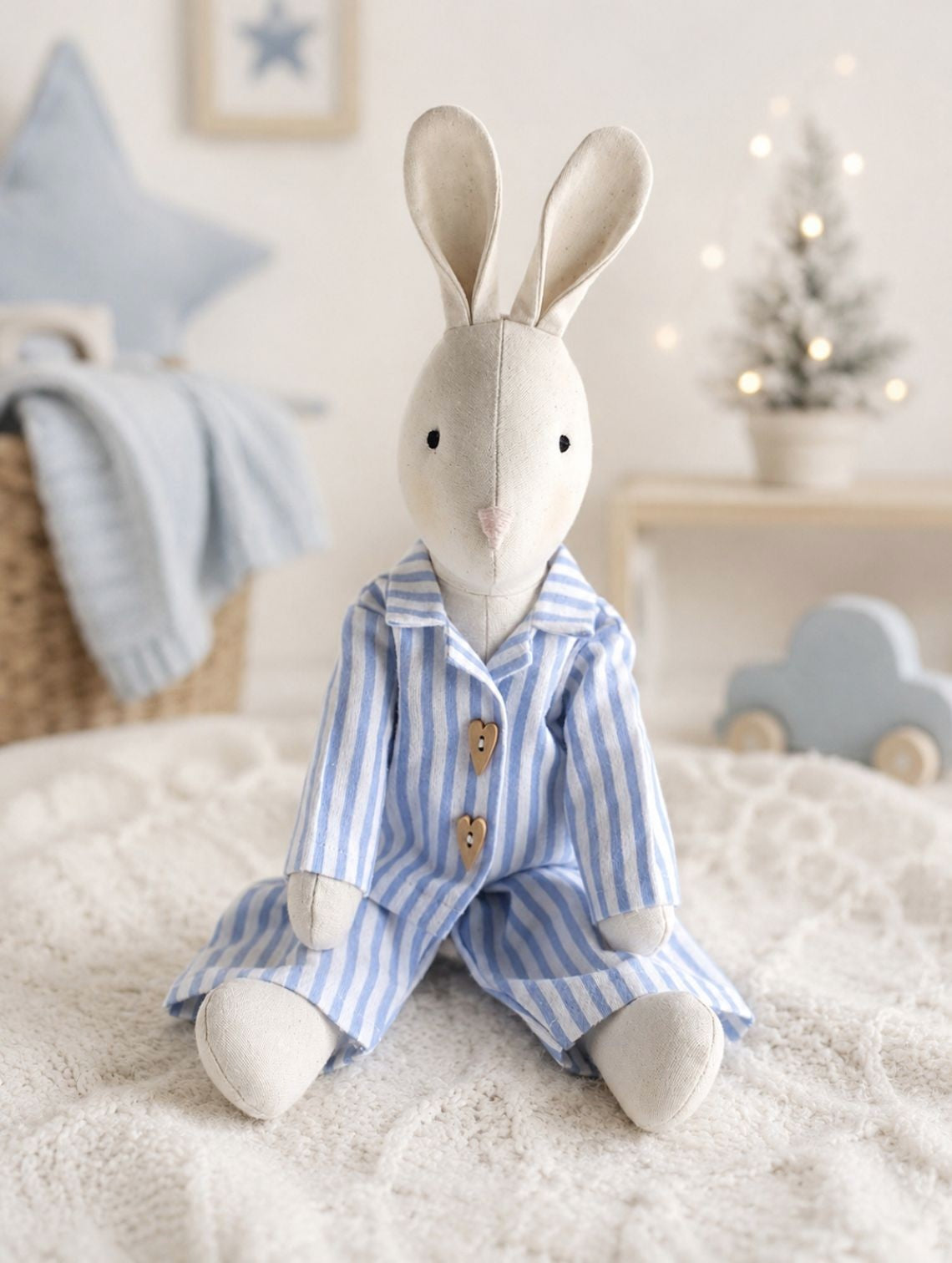 Handmade linen Gerald Bunny wearing blue striped pyjamas in a pale Christmas nursery setting.