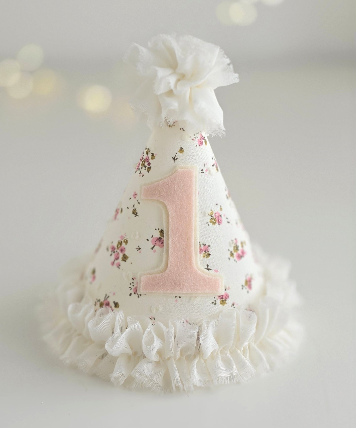 Ditsy floral first birthday party hat with pale pink number 1 and white chiffon ruffle trim and pompom on top.