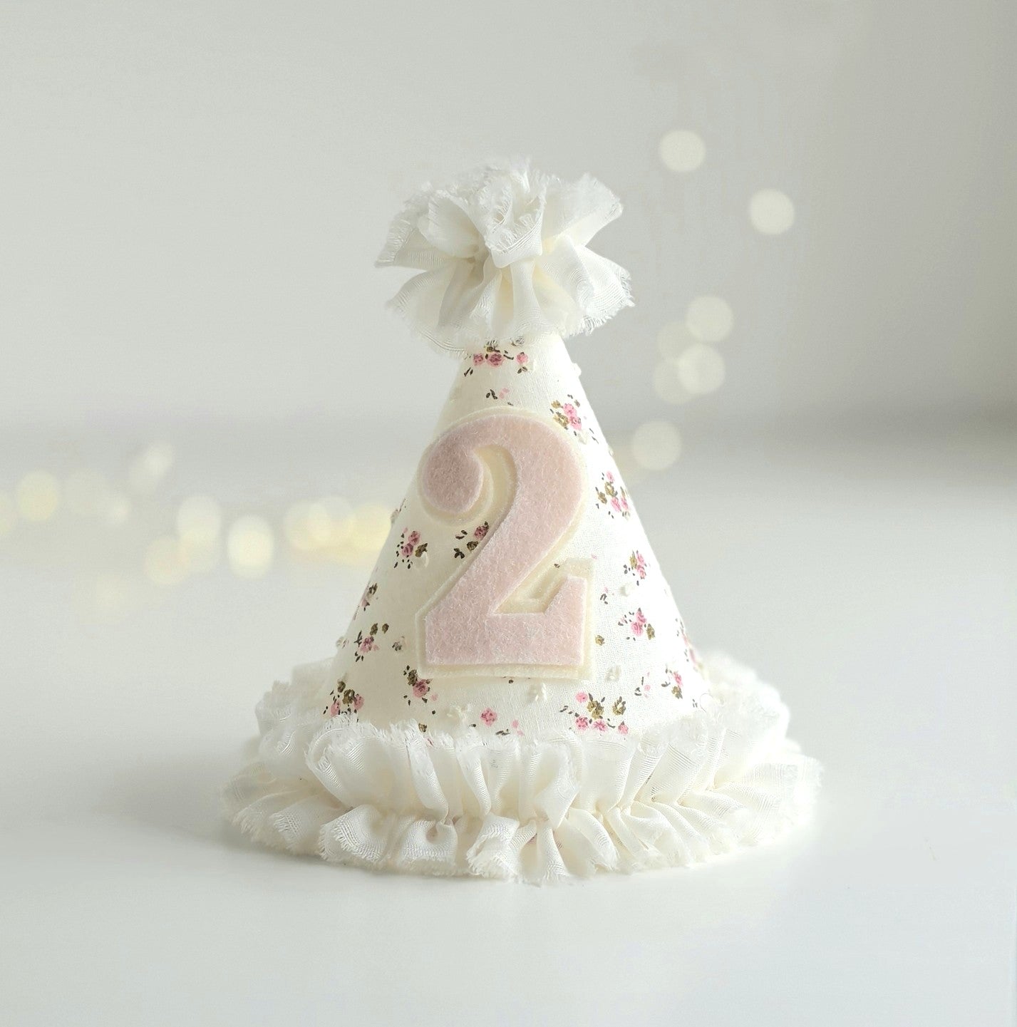 Ditsy floral second birthday party hat with pale pink number 2 and white chiffon ruffle trim with matching pompom on top.