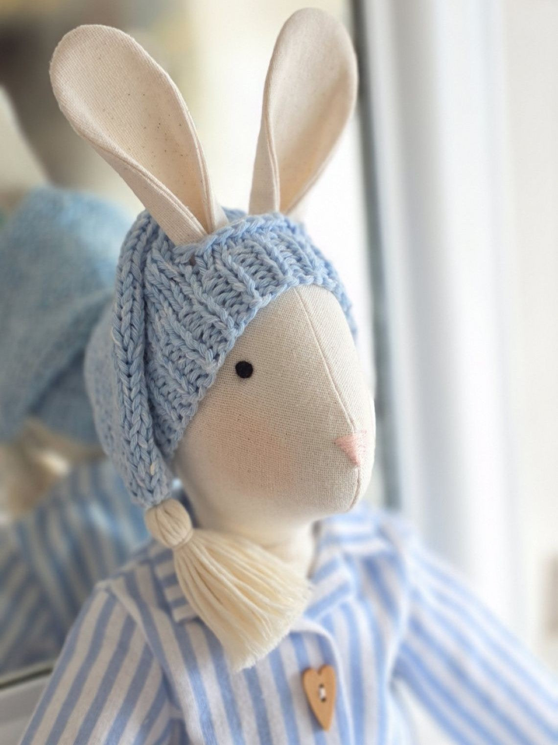 Close-up of Gerald Bunny wearing a hand-knitted blue sleepy hat and blue striped pyjamas.