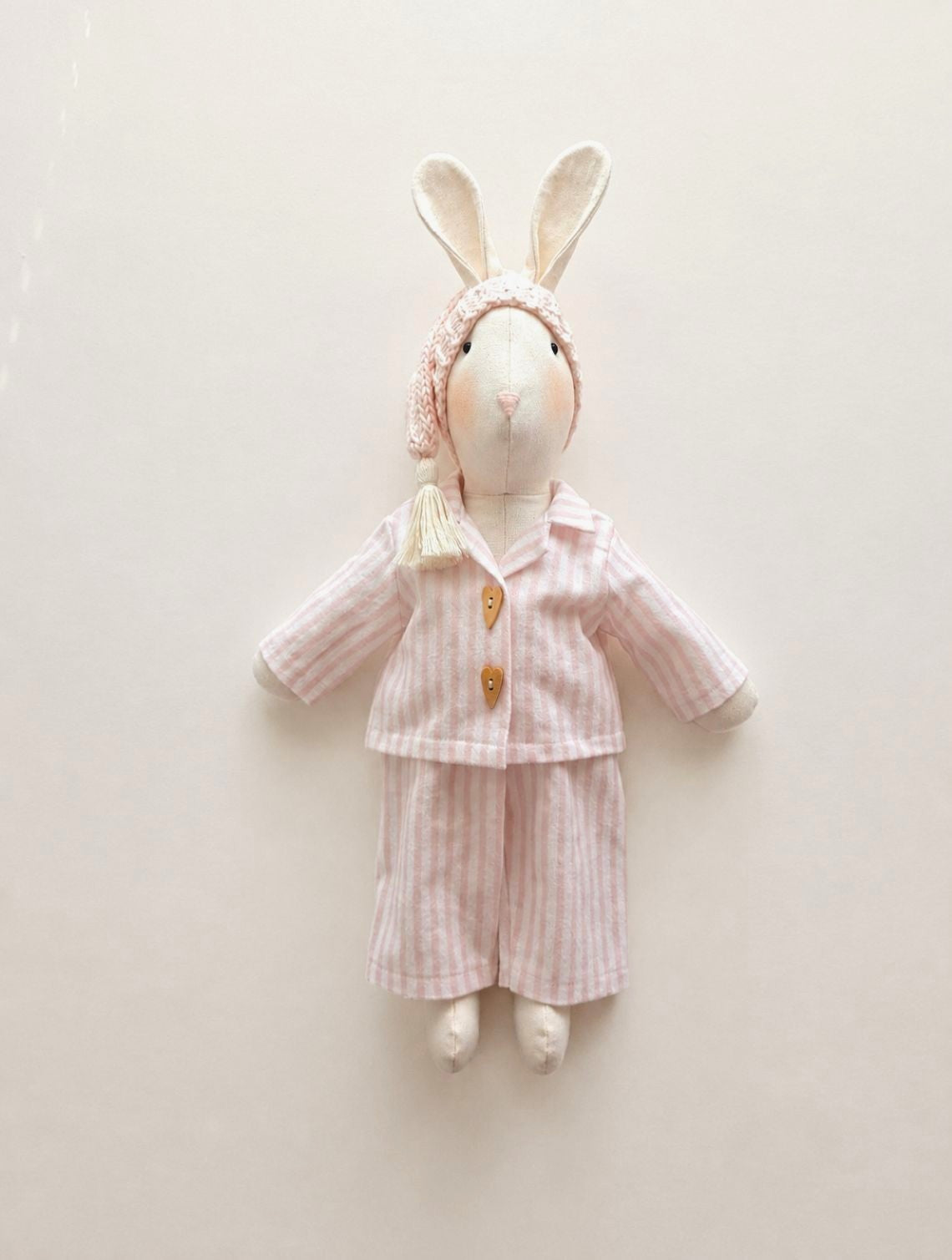 Full-length handmade linen Veronica Bunny wearing pink striped pyjamas and a pale pink knitted sleepy hat.
