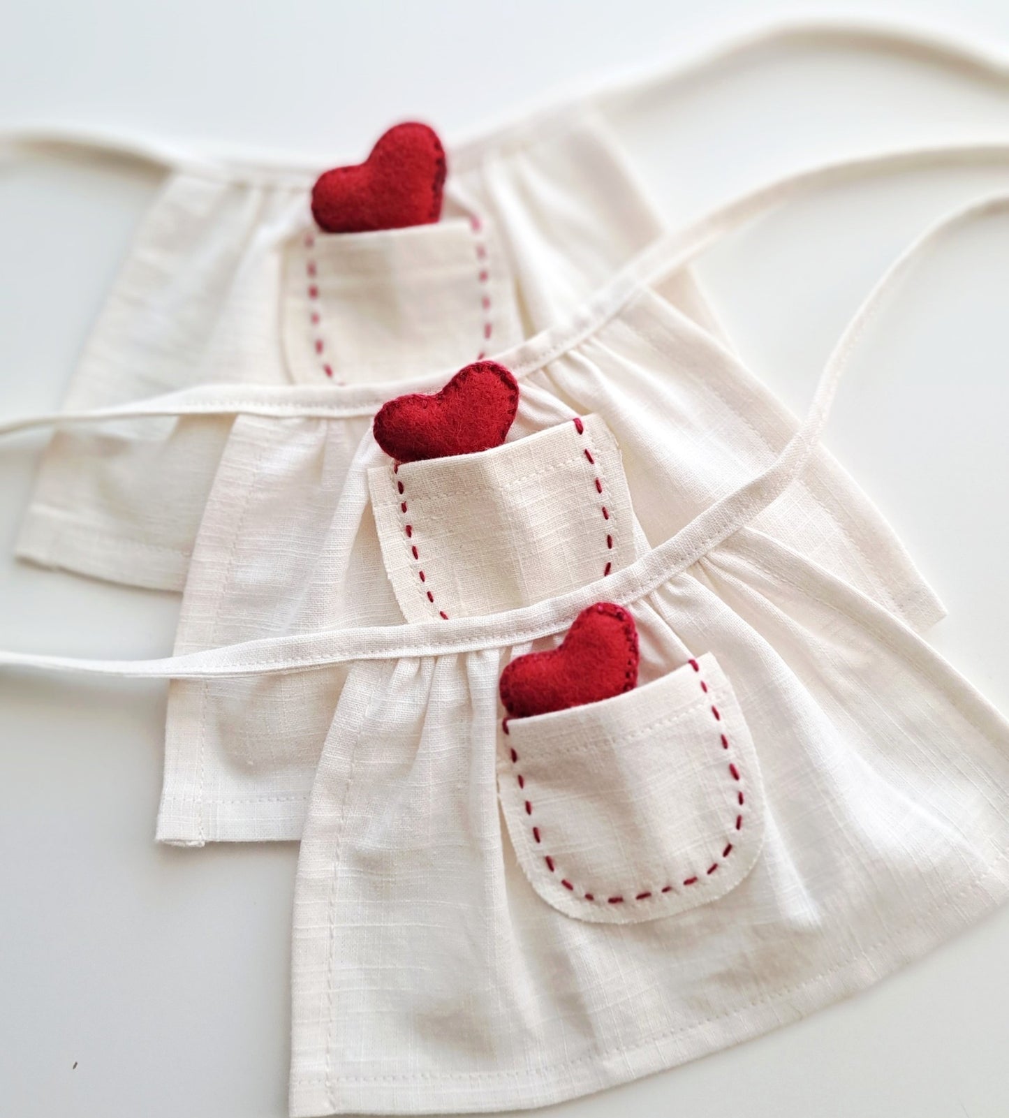 Close-up of a handmade linen apron with hand stitched pocket and red felt heart on a Veronica Bunny Valentine’s outfit