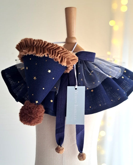 Midnight Halloween set displayed on mannequin — matching navy linen cape with star tulle layers and coordinating party hat with pom-pom and ruffle trim.